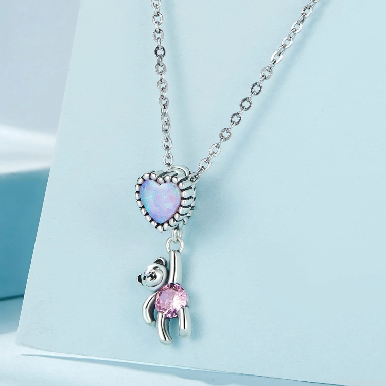Uniwersalna srebrna zawieszka do bransoletki modułowej lub naszyjnika, Miś z różowym kryształem trzymający się opalizującego serca