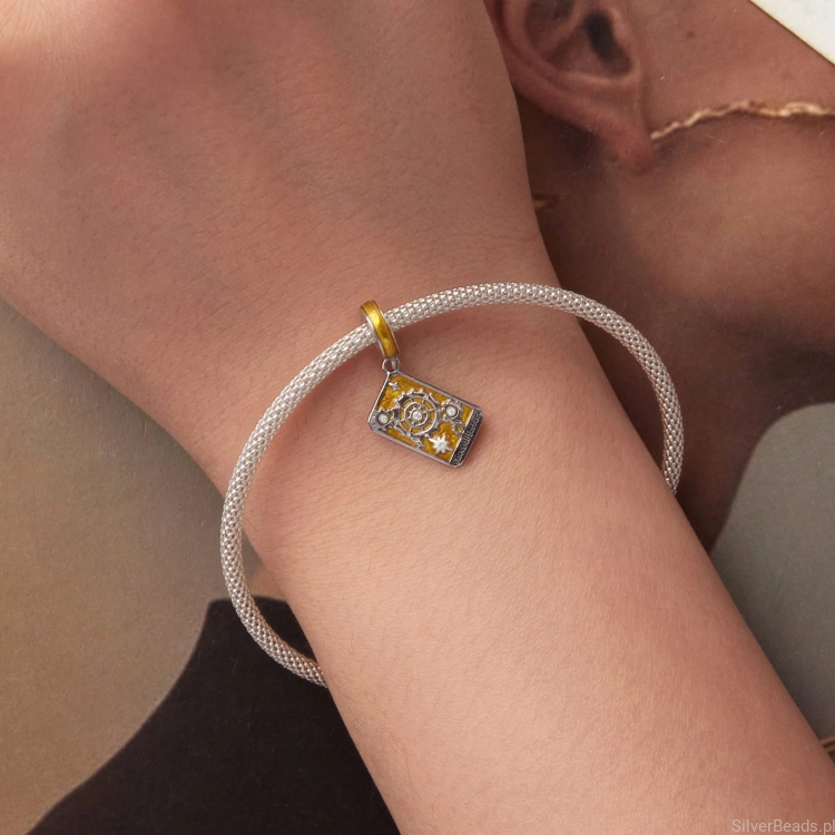 Symboliczny charms „Koło Fortuny” z połyskującymi detalami.